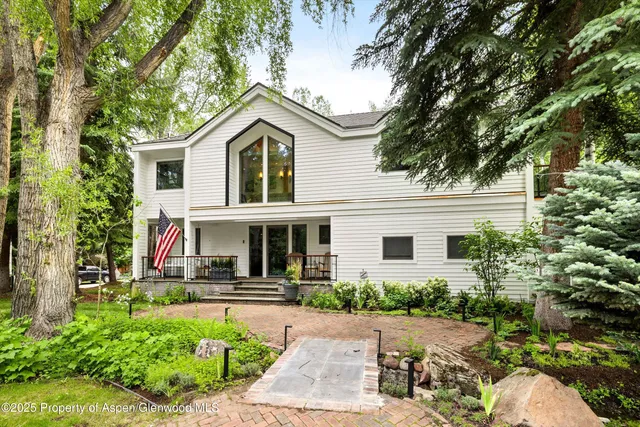 a view of a house with a small yard plants and large tree