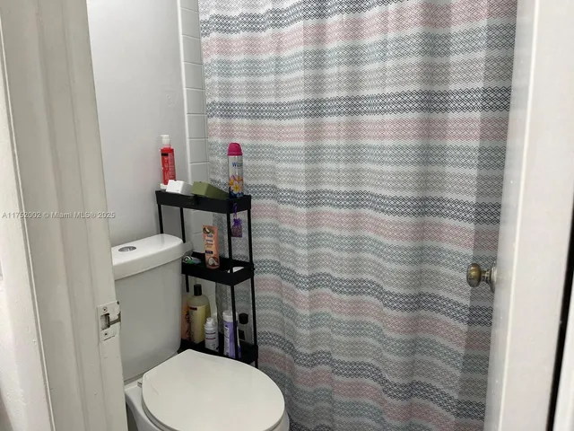 a bathroom with a toilet and a shower curtain