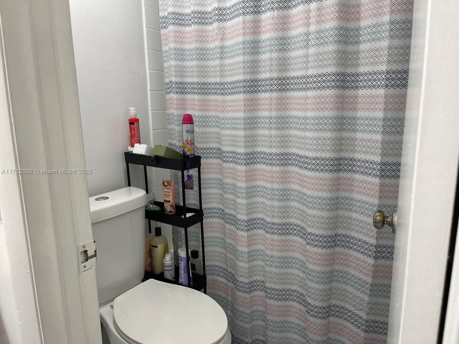 21133 Southwest 85th Avenue, Unit 112 Cutler Bay, FL 33189 - Photo 11 of 18 a bathroom with a toilet and a shower curtain