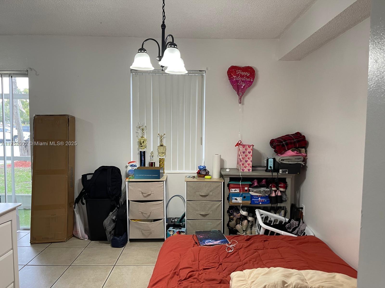 21133 Southwest 85th Avenue, Unit 112 Cutler Bay, FL 33189 - Photo 8 of 18 a bedroom with a bed and a chandelier