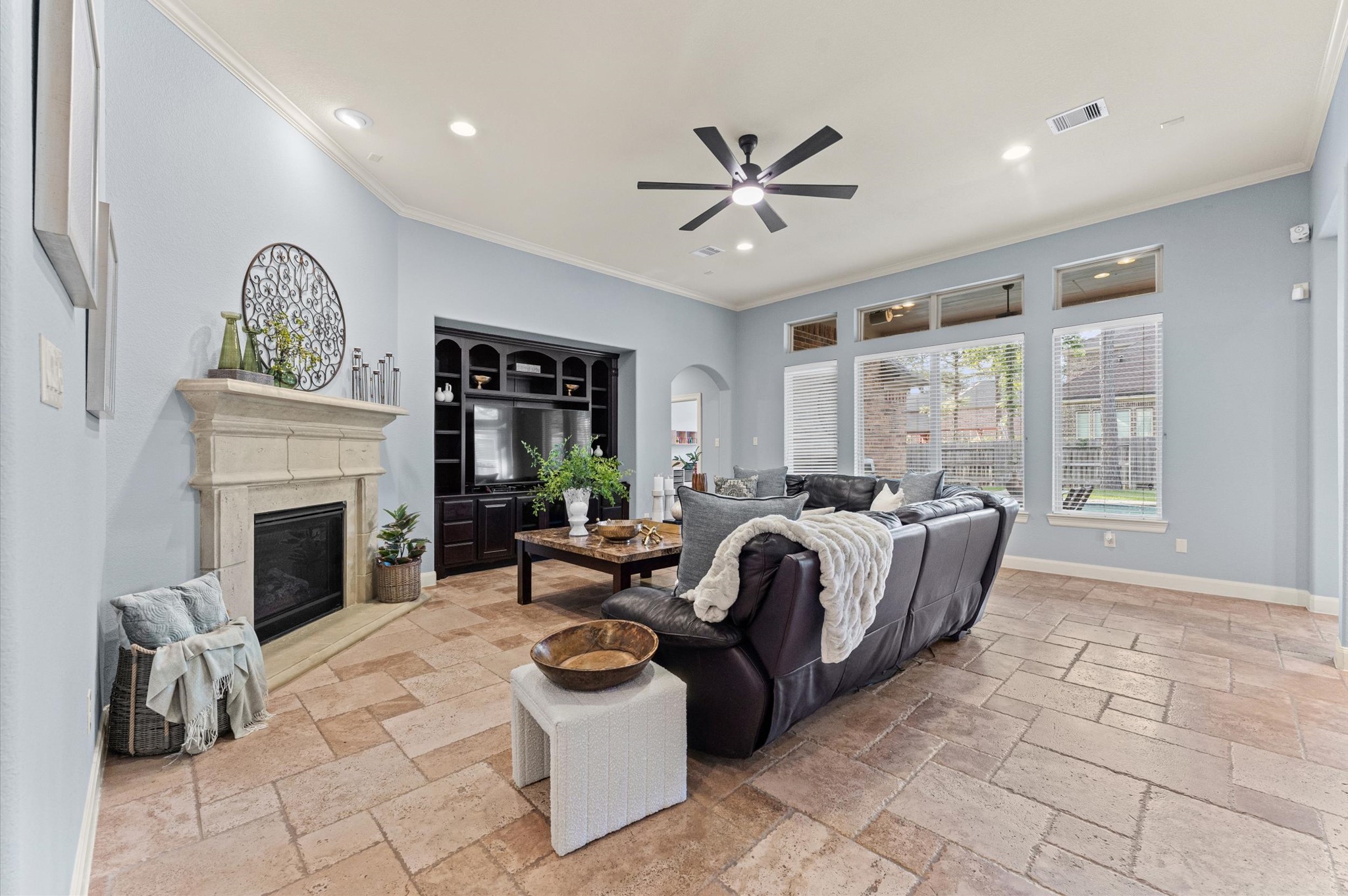 70 Valera Ridge Drive Spring, TX 77389 - Photo 11 of 37 Spacious living room with large windows, high ceilings, and natural light. Features include a cozy fireplace, modern ceiling fan, built-in entertainment unit, and stylish tile flooring. Ideal for comfort and entertaining.