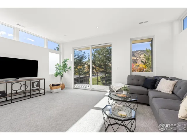 a living room with furniture a flat screen tv and a large window