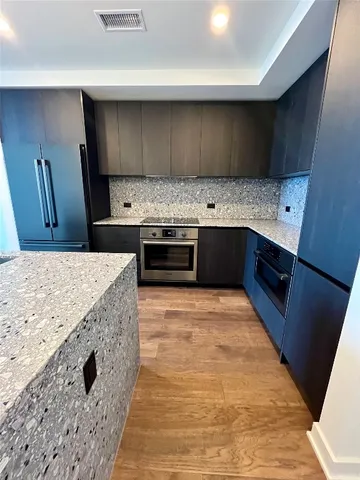 a large kitchen with granite countertop a sink a stove top oven and wooden cabinets