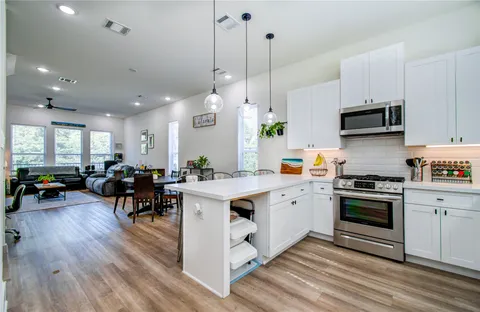a kitchen with a sink stove and white cabinets with wooden floor