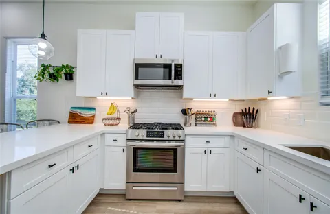 a kitchen with cabinets stainless steel appliances and wooden floor