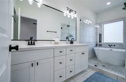 a bathroom with a double vanity sink mirror and bathtub