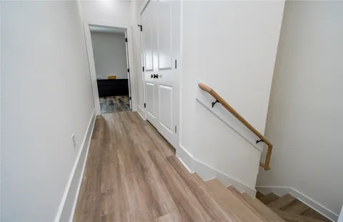 a view of a hallway with wooden floor and staircase