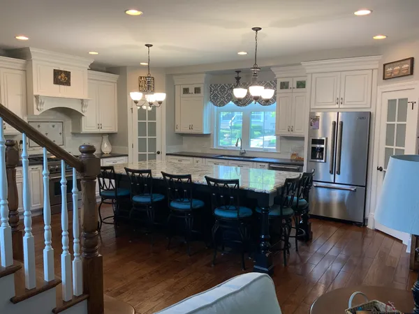 a kitchen with stainless steel appliances granite countertop a refrigerator a stove a sink dishwasher a dining table and chairs with wooden floor