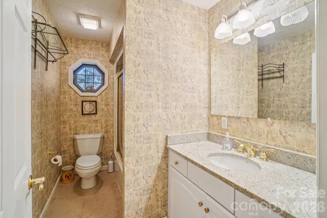 a bathroom with a granite countertop toilet sink and mirror