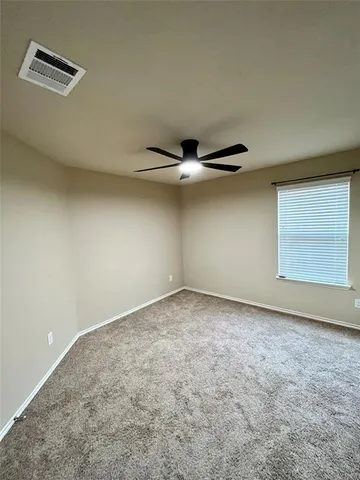 an empty room with windows and ceiling fan