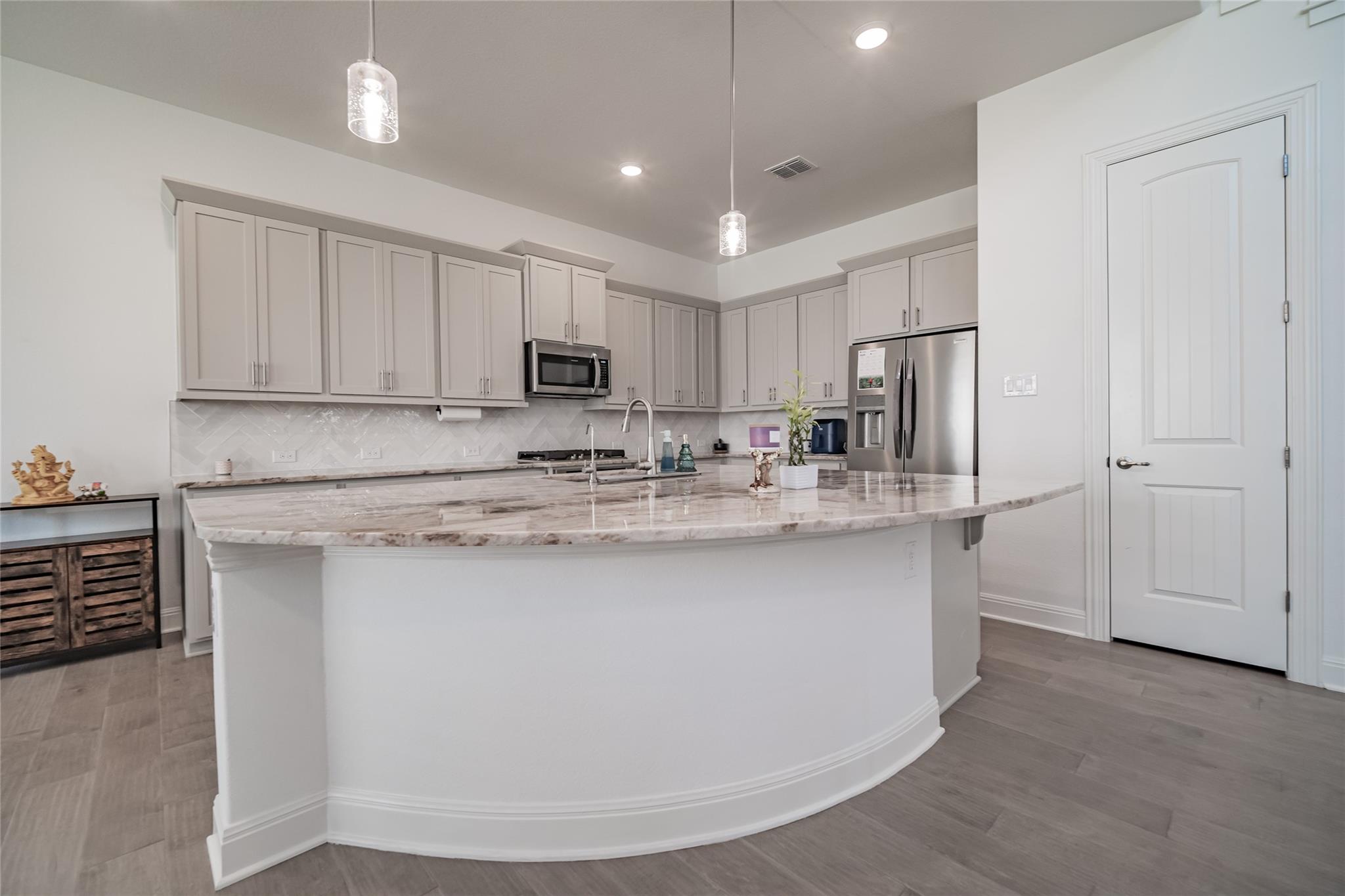 3049 Sage Ranch Drive Leander, TX 78641 - Photo 3 of 23 An inviting kitchen with light wood flooring offers ample granite countertop space and modern stainless steel appliances.