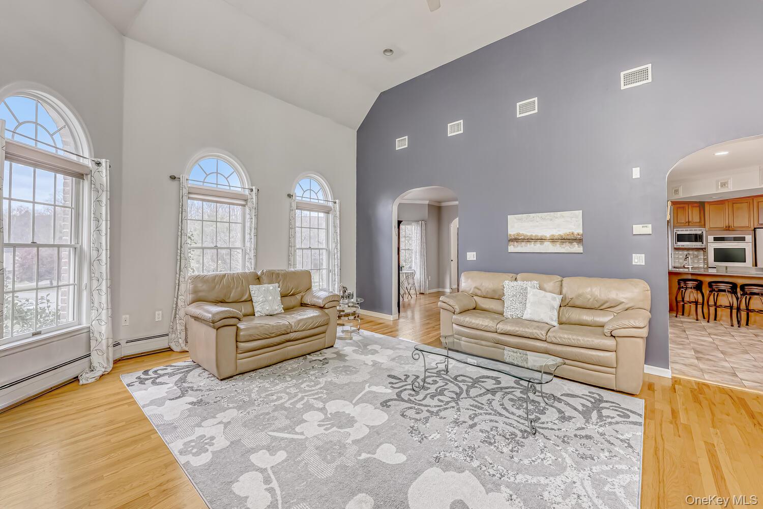 22 Golden Road Suffern, NY 10901 - Photo 16 of 41 Living area with arched walkways, high vaulted ceiling, light wood-style flooring, and baseboard heating