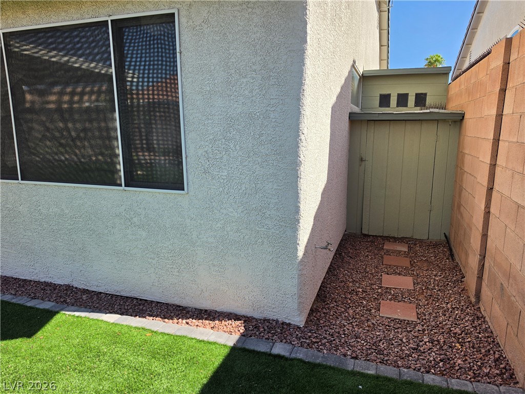 209 Opera House Street Henderson, NV 89012 - Photo 42 of 45 Stucco exterior finishes pair with a block wall border and stepping stones.