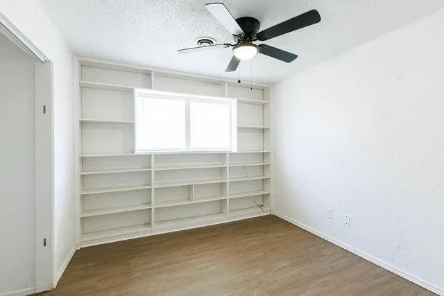 a view of an empty room with a window and a ceiling fan