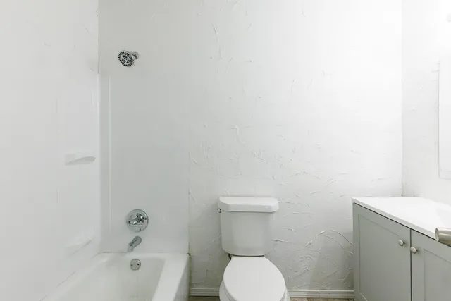 a white toilet sitting next to a bath tub