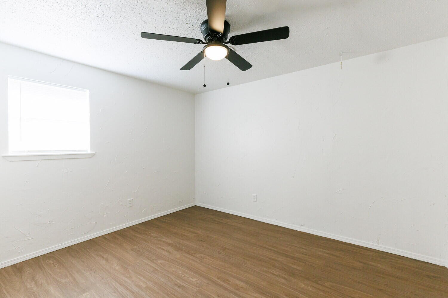 5517 16th Place Lubbock, TX 79416 - Photo 18 of 23 an empty room with wooden floor fan and windows