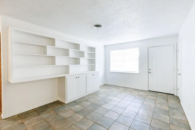 a view of an empty room with window and cabinet