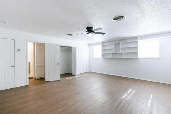 an empty room with wooden floor and windows