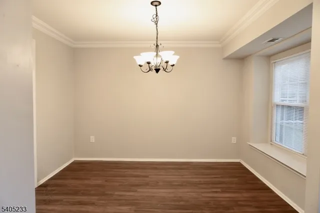 a view of a room with wooden floor chandelier and a window