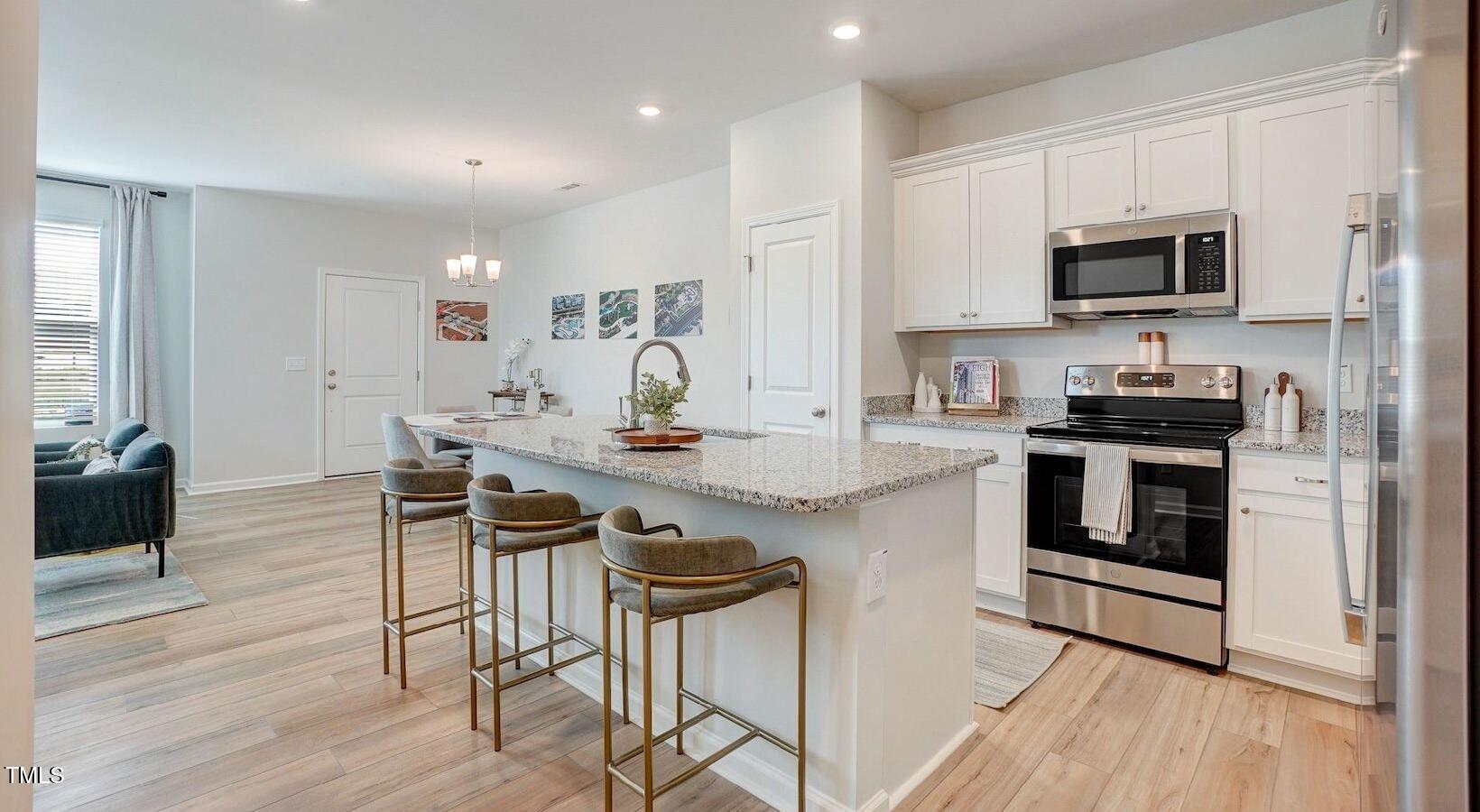101 Decatur Drive Raleigh, NC 27603 - Photo 20 of 24 a kitchen with stainless steel appliances kitchen island granite countertop a stove top oven a sink a dining table and chairs with wooden floor
