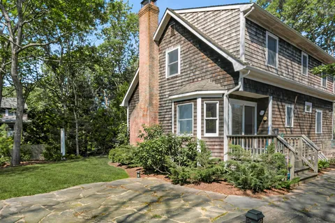 a view of a house with brick walls and a yard with plants
