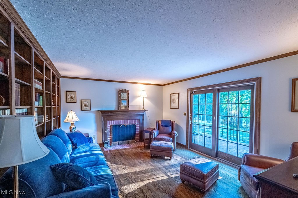 1252 New England Ridge Road Washington, WV 26181 - Photo 14 of 50 Living room featuring a textured ceiling, crown molding, wood finished floors, and a fireplace