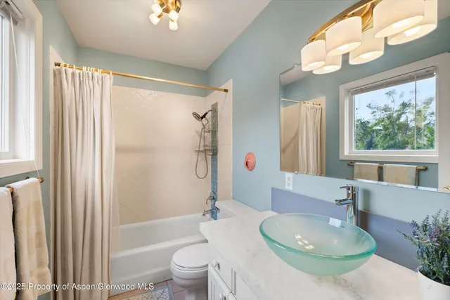 a bathroom with a granite countertop bathtub sink vanity mirror and toilet