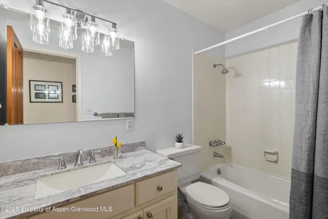 a bathroom with a granite countertop sink toilet a large mirror a shower and a bathtub