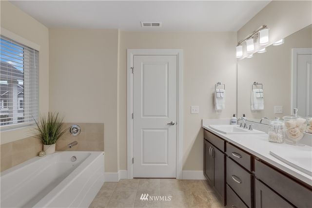 a bathroom with a tub a sink and mirror