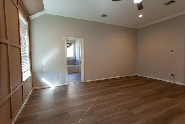 an empty room with wooden floor and windows