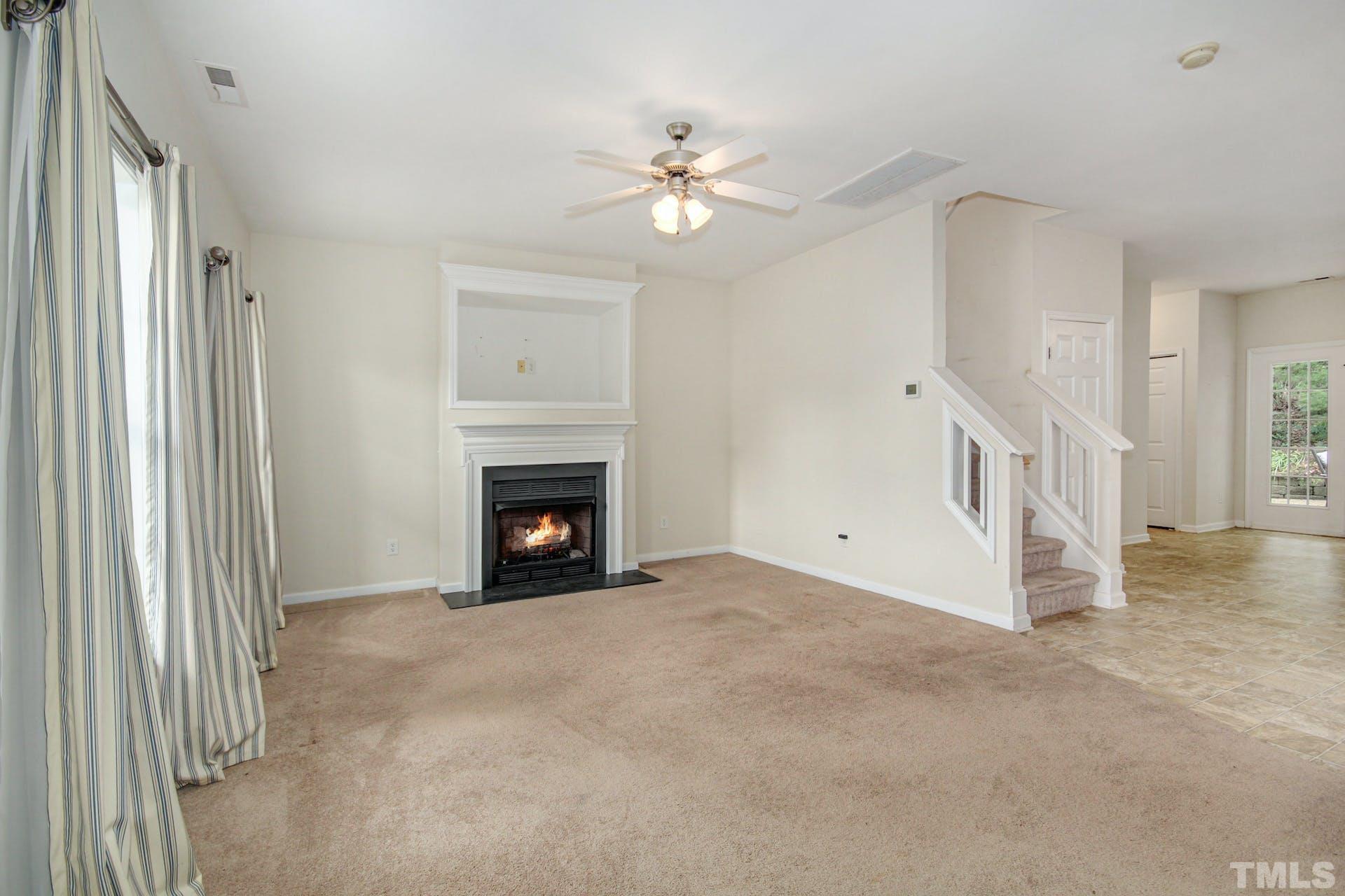 5852 Wynmore Road Raleigh, NC 27610 - Photo 4 of 25 a view of a livingroom with a fireplace a ceiling fan and windows