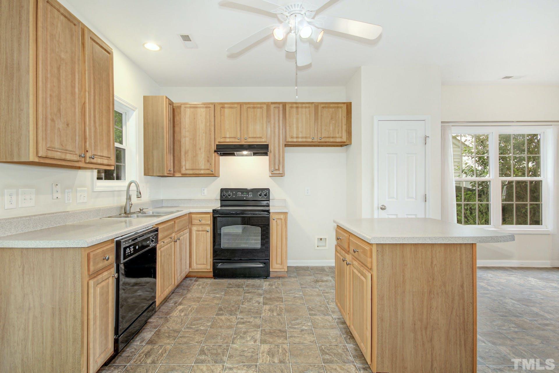 5852 Wynmore Road Raleigh, NC 27610 - Photo 10 of 25 a kitchen with stainless steel appliances a stove sink and cabinets