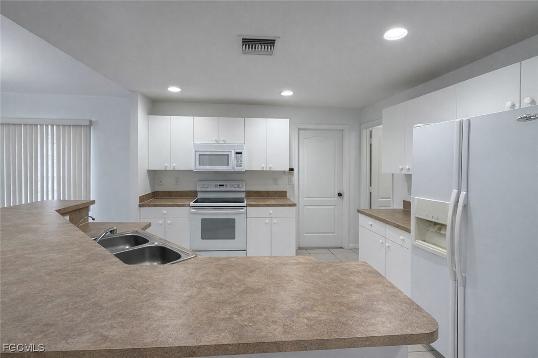 3215 13th Street Southwest Lehigh Acres, FL 33976 - Photo 4 of 12 a kitchen with a refrigerator and white cabinets