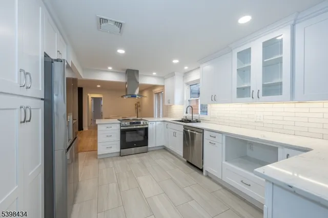 a large kitchen with a large counter top a sink stainless steel appliances and cabinets