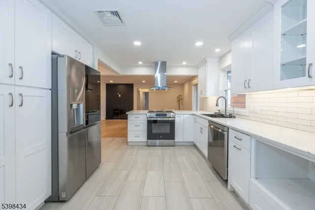 a large kitchen with a large counter top stainless steel appliances and cabinets