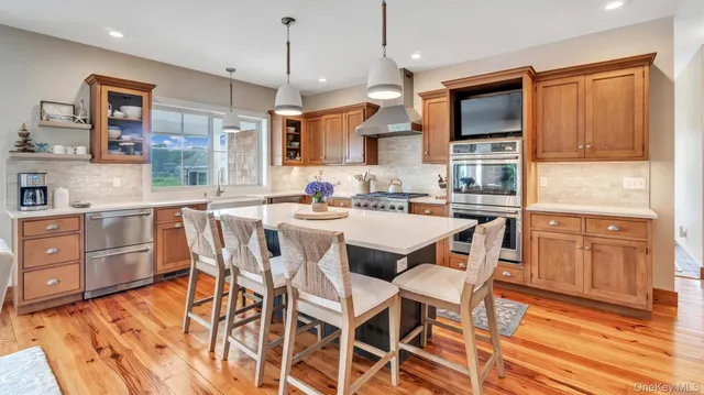 a dining area with stainless steel appliances granite countertop a sink a stove a dining table and chairs with wooden floor