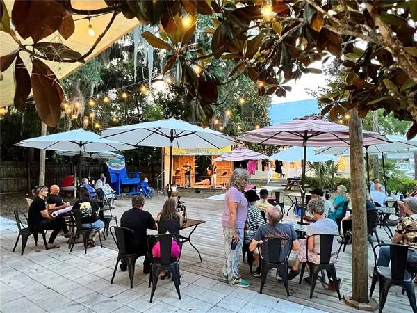 a group of people sitting under an umbrella in front of retail shops