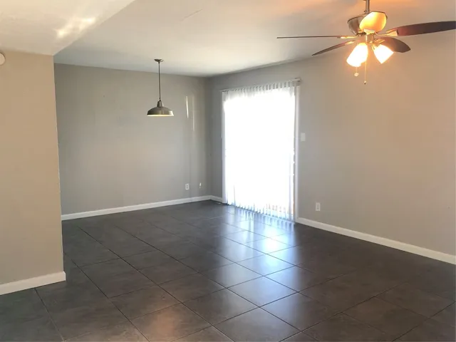 en empty room with windows and ceiling fan