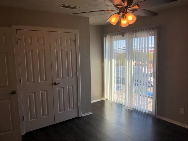 an empty room with wooden floor and windows with curtains