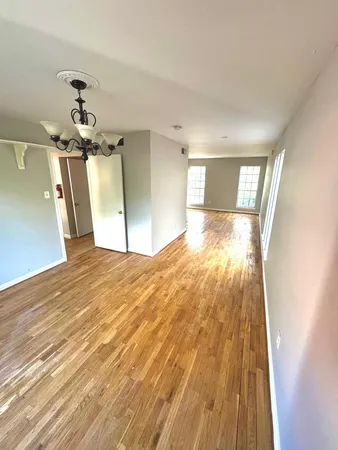 a view of a big room with wooden floor a chandelier fan and windows