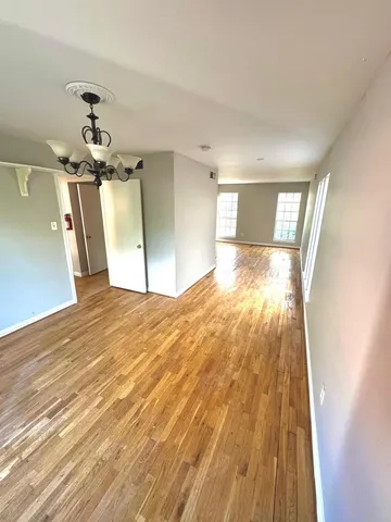 a view of a big room with wooden floor a chandelier fan and windows
