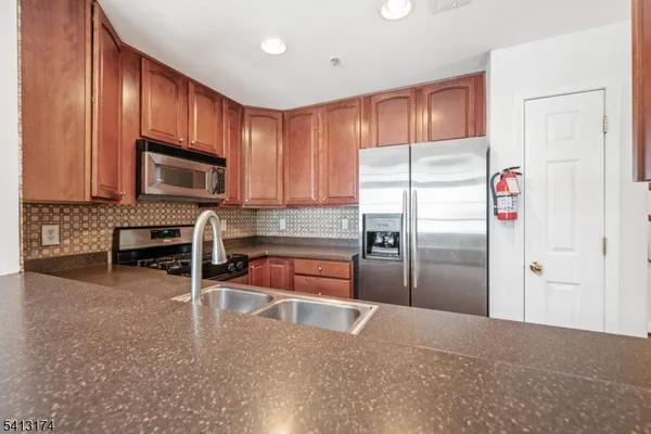 a kitchen with granite countertop a refrigerator and a stove top oven