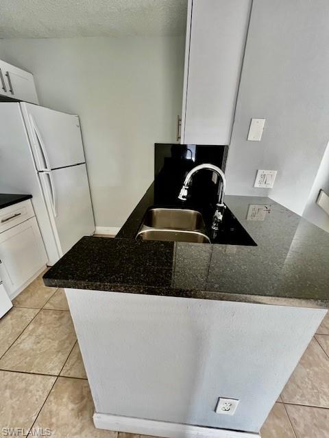142 Santa Clara Drive, Unit 7 Naples, FL 34104 - Photo 12 of 41 Kitchen featuring a peninsula, a sink, white cabinets, and freestanding refrigerator