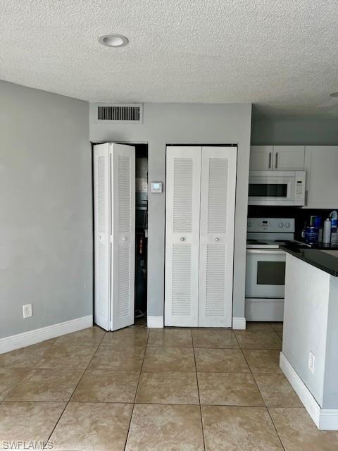 142 Santa Clara Drive, Unit 7 Naples, FL 34104 - Photo 13 of 41 Kitchen featuring visible vents, white cabinetry, white appliances, dark countertops, and a textured ceiling