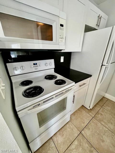 142 Santa Clara Drive, Unit 7 Naples, FL 34104 - Photo 14 of 41 Kitchen with light tile patterned floors, dark countertops, white cabinetry, and white appliances