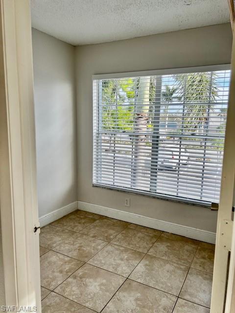 142 Santa Clara Drive, Unit 7 Naples, FL 34104 - Photo 21 of 41 Empty room featuring light tile patterned floors, a textured ceiling, baseboards, and a healthy amount of sunlight