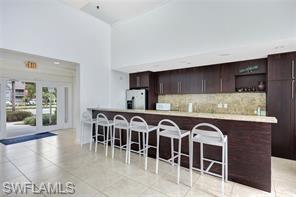142 Santa Clara Drive, Unit 7 Naples, FL 34104 - Photo 27 of 41 Kitchen with tasteful backsplash, freestanding refrigerator, dark brown cabinetry, light countertops, and a breakfast bar area