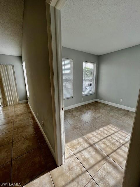 142 Santa Clara Drive, Unit 7 Naples, FL 34104 - Photo 6 of 41 Hall with tile patterned flooring, a textured ceiling, and baseboards