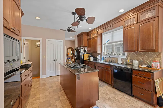 a kitchen with stainless steel appliances granite countertop a stove refrigerator and couches with wooden floor