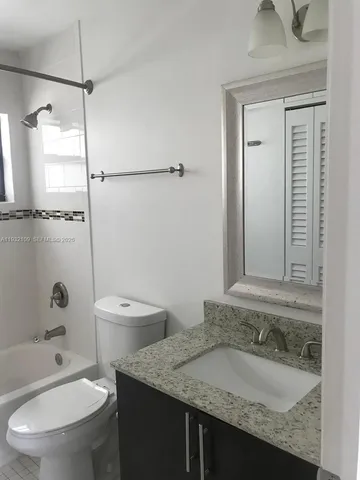 a bathroom with a granite countertop sink toilet a mirror and shower